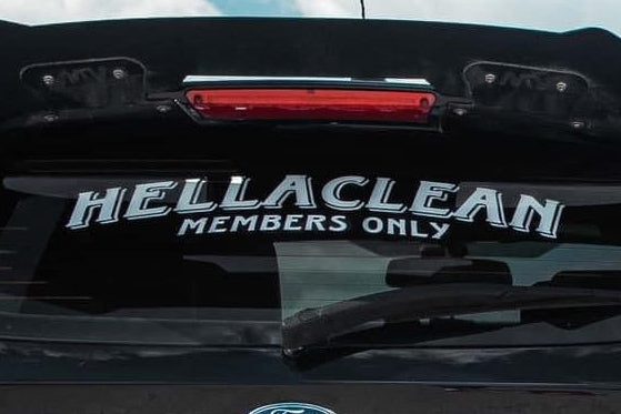 Black car on a rural road with a clear blue sky